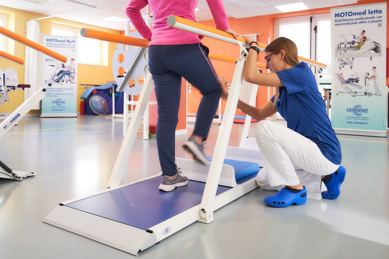 Una specialista assiste una persona impegnata in esercizi riabilitativi sul tapis roulant